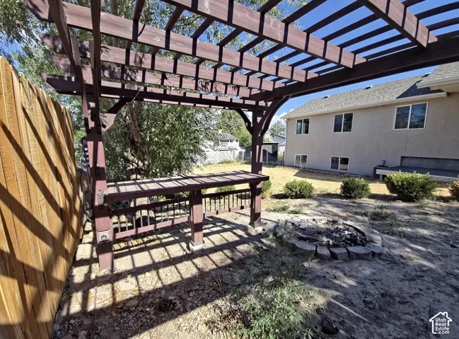 Backyard featuring a wood pergola with a built-in bar, a stone-edged fire pit, and a privacy fence