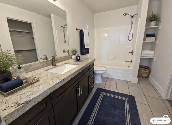 Vanity with a light-toned stone countertop, integrated sink, and dark wood-finish cabinetry