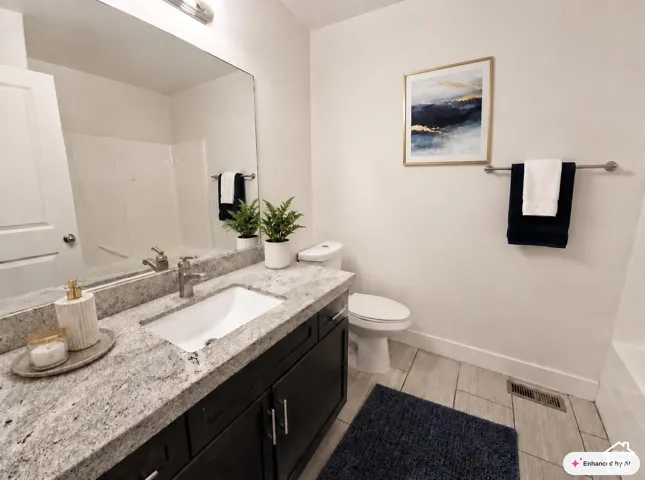 Spacious vanity with a light granite countertop, undermount sink, and dark wood-finish cabinetry