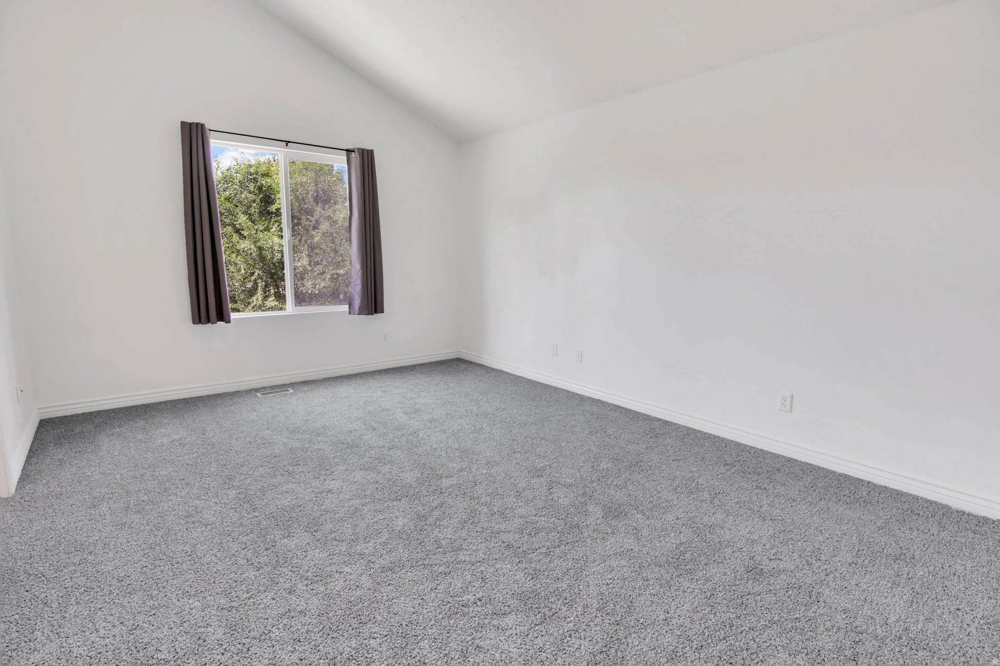 Room featuring vaulted ceilings and gray carpeting