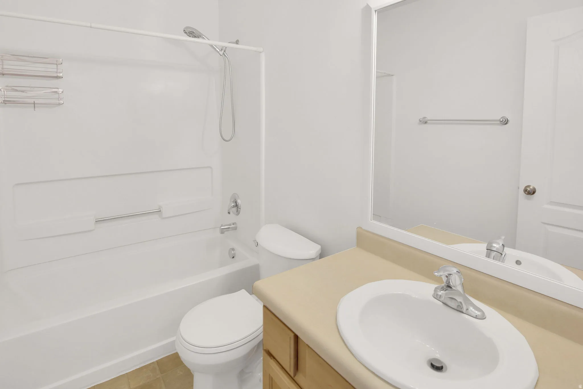 Bathroom featuring a white bathtub with an integrated shower, a toilet, and a vanity with an integrated sink and light-toned countertop