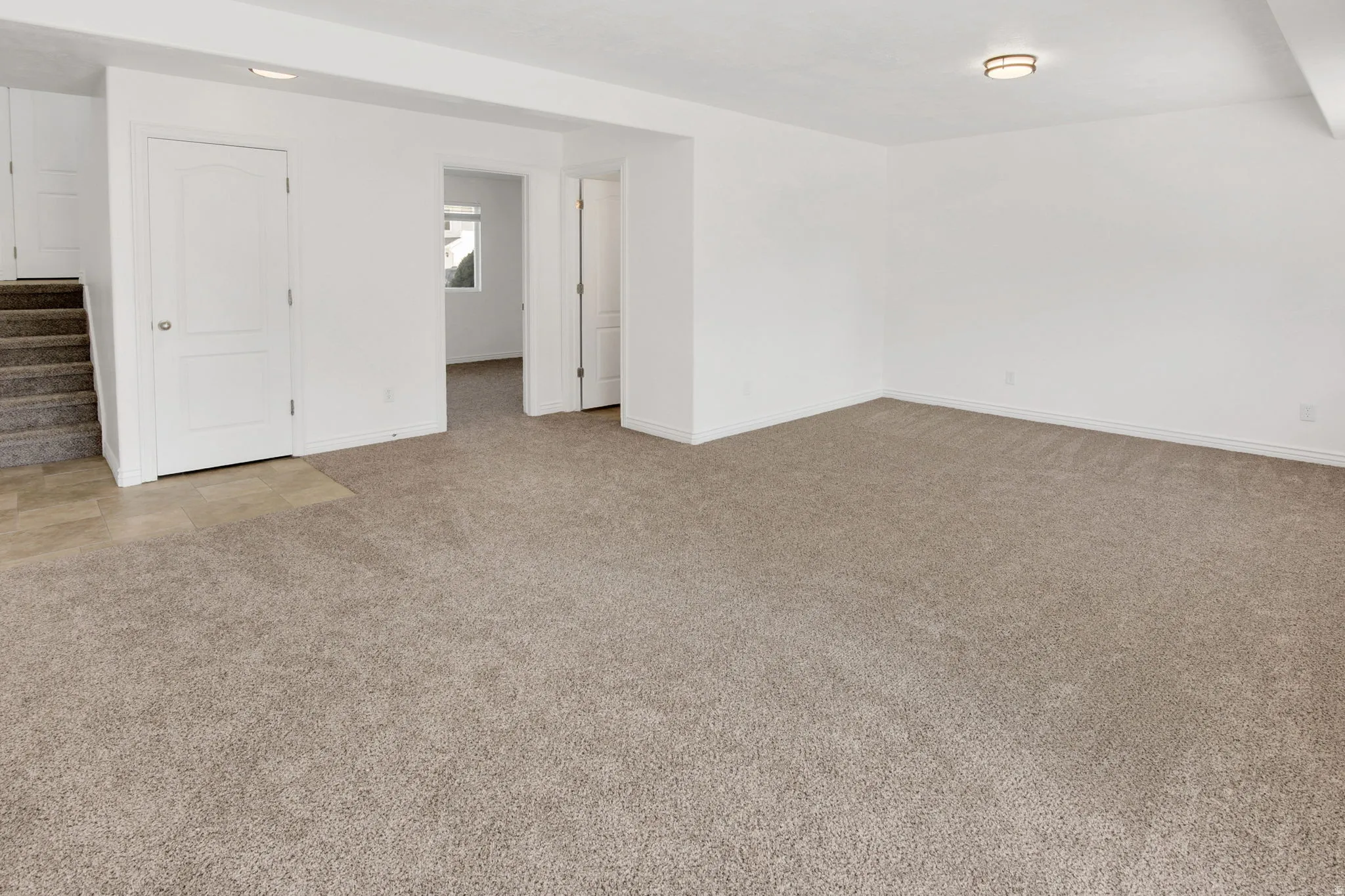 Spacious room featuring neutral carpeting, white painted walls, white trim, recessed lighting, and a flush mount ceiling fixture