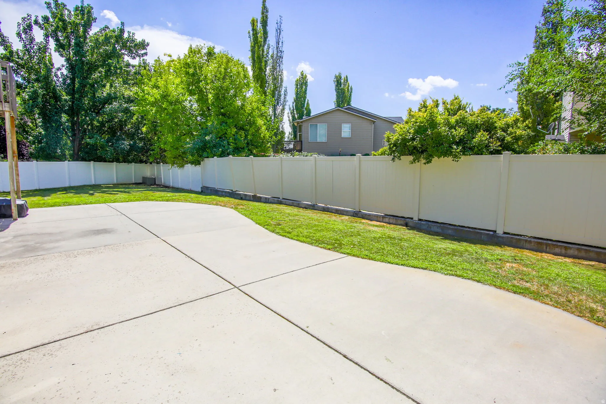 Expansive concrete patio area with a surrounding vinyl privacy fence