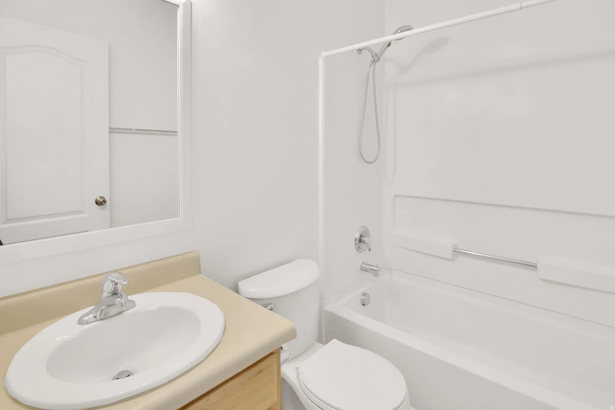 Bathroom featuring a white bathtub and shower combination, chrome fixtures, a toilet, a vanity with a laminate countertop, and an oval undermount sink