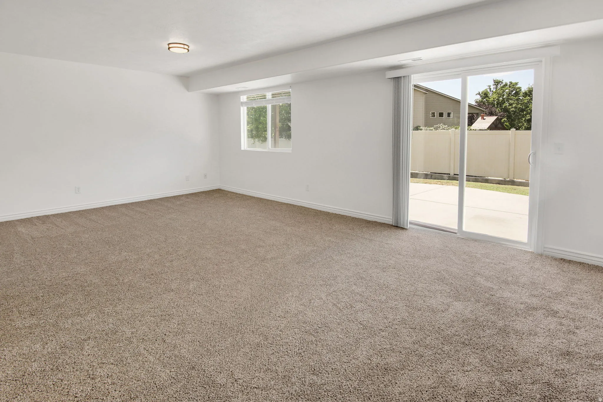 Spacious room featuring neutral carpeting, white walls, and a contemporary flush-mount ceiling light