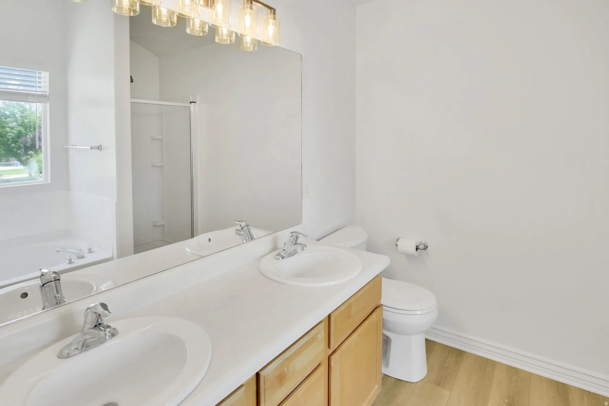 Dual vanity with white undermount sinks, light wood-finish cabinetry, and chrome fixtures