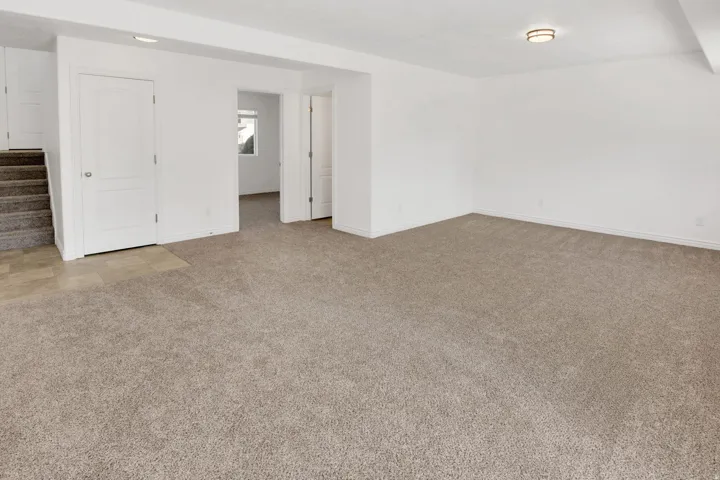 Spacious room featuring neutral carpeting, white painted walls, white trim, recessed lighting, and a flush mount ceiling fixture