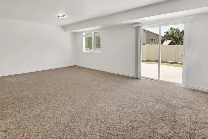 Spacious room featuring neutral carpeting, white walls, and a contemporary flush-mount ceiling light