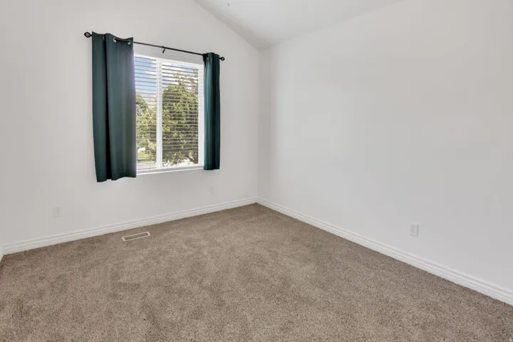 Bright room featuring vaulted ceilings and neutral-toned carpeting
