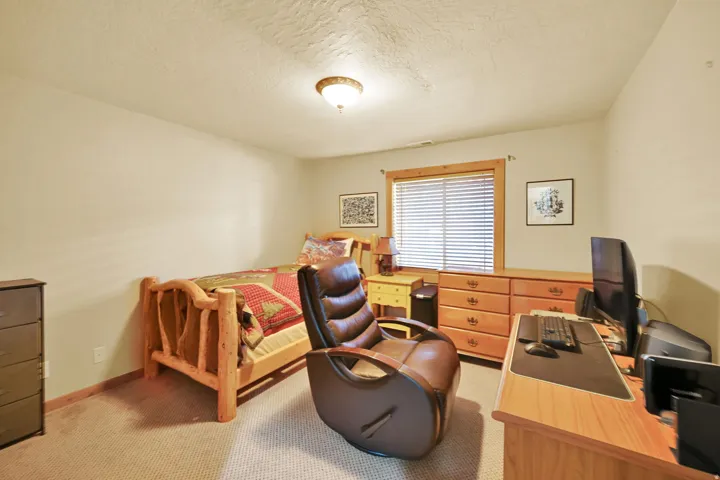 Carpeted room featuring a window with blinds, wood-trim, and a built-in wood dresser