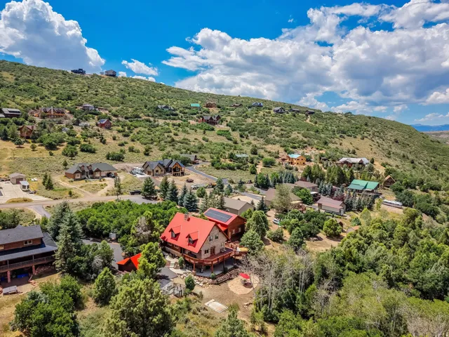 Hillsides featuring numerous homes, expansive green spaces, and a prominent red-roofed residence