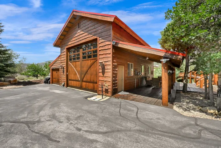 Wood-sided structure featuring a red roof and a large garage door with window inserts