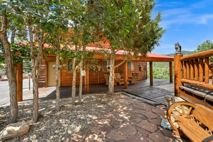 Wood-sided property featuring a covered porch with exposed beams and a red roof