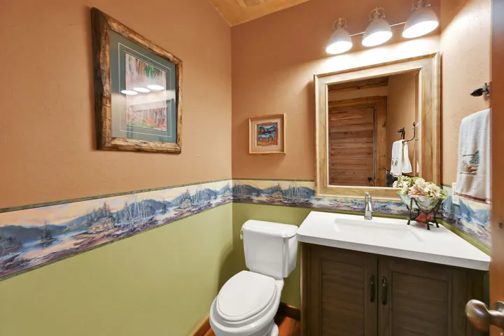 Bathroom featuring a corner vanity with a white countertop and integrated sink, a large framed mirror, and a wall-mounted light fixture