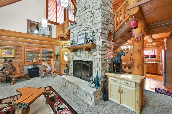 Stone-clad fireplace extending to the ceiling, featuring a prominent wood mantel and hearth