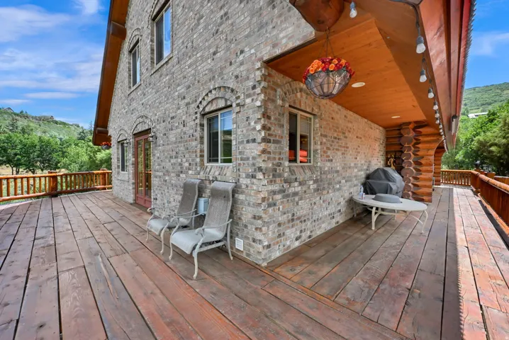 Expansive wood deck with natural wood railing, featuring a brick exterior with arched windows and a log-style accent wall