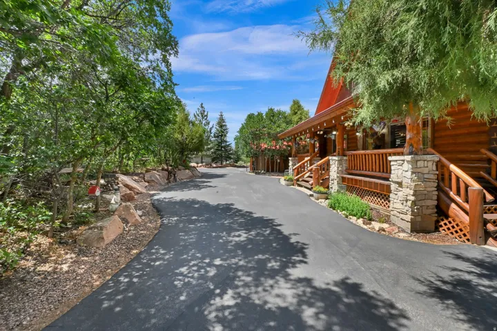 Inviting log cabin exterior featuring a covered porch, stone pillars, and multiple steps