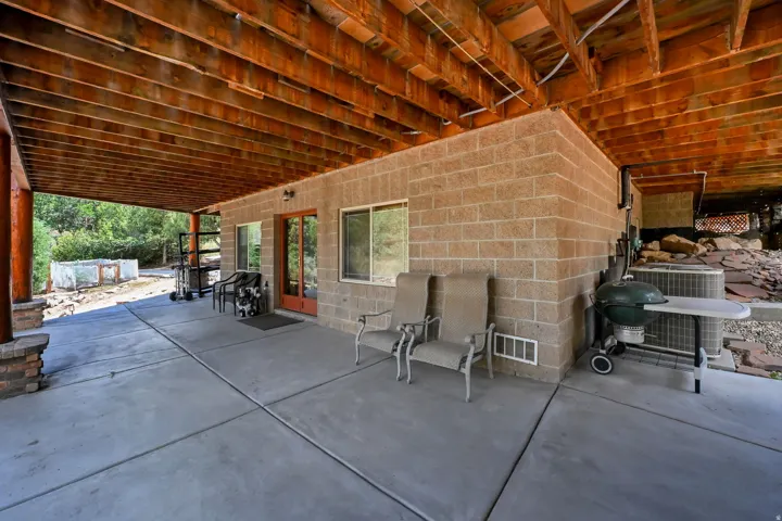 Expansive covered patio featuring a concrete surface, exposed wood beam ceiling, and a block wall exterior