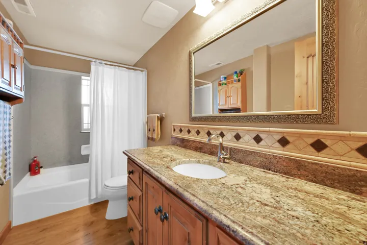 Bathroom featuring a single vanity with granite-style countertop, wood cabinetry, and a framed mirror