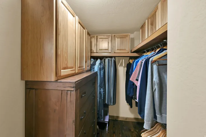 Custom closet with extensive wood cabinetry, dedicated hanging rods, and built-in upper storage
