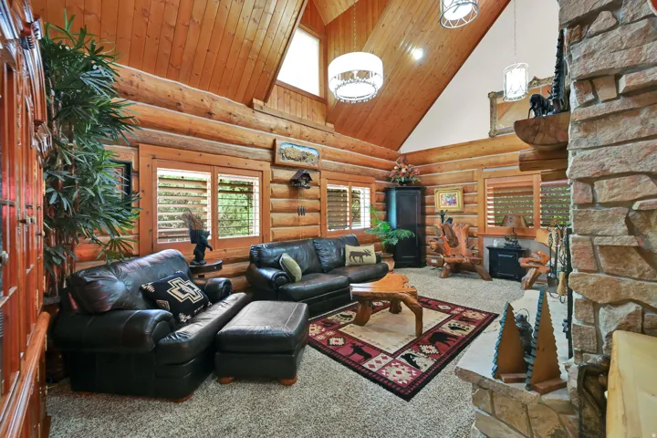 Vaulted wood-paneled ceilings, log walls, and a stone fireplace define this living space