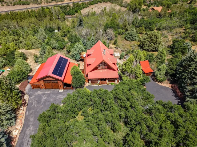 Rustic-style main residence with a vibrant red metal roof and stone foundation accents