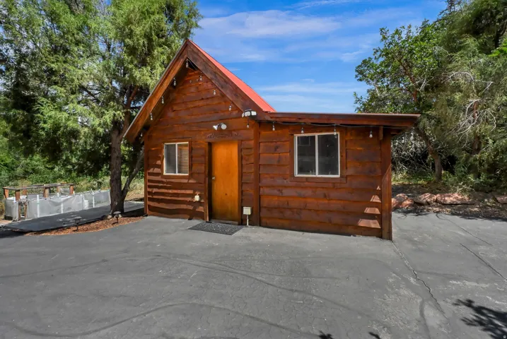 Wood-sided cabin structure featuring a prominent red roof and pitched gables