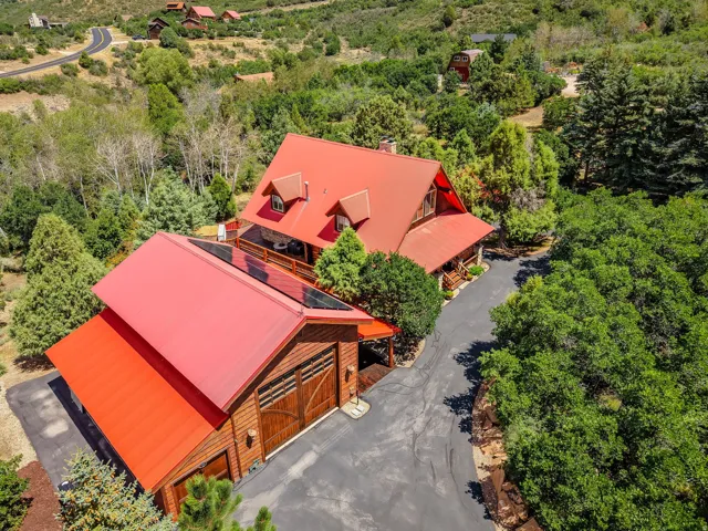 Property featuring a prominent red metal roof, a multi-car garage with wood doors, and solar panels