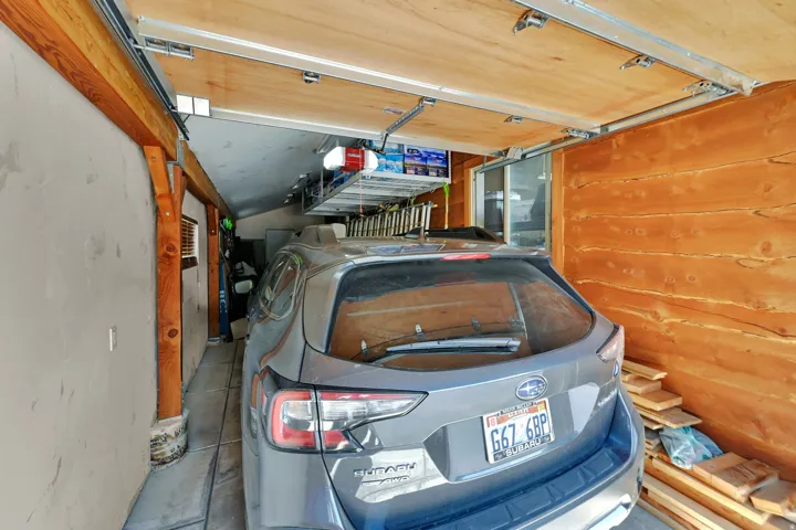 Garage interior featuring a wood-panel ceiling, exposed timber beams, and wood-finish wall paneling