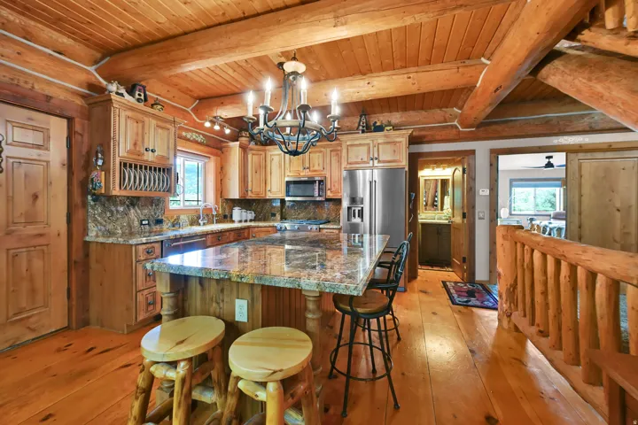 Kitchen featuring wood-finish flooring, exposed wood beam ceiling, wood cabinetry, stone countertops, and stainless steel appliances
