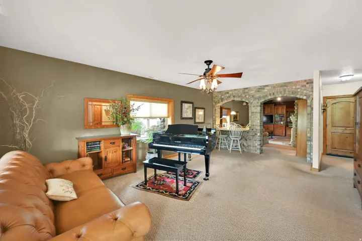 Spacious living area featuring neutral carpeting and a ceiling fan
