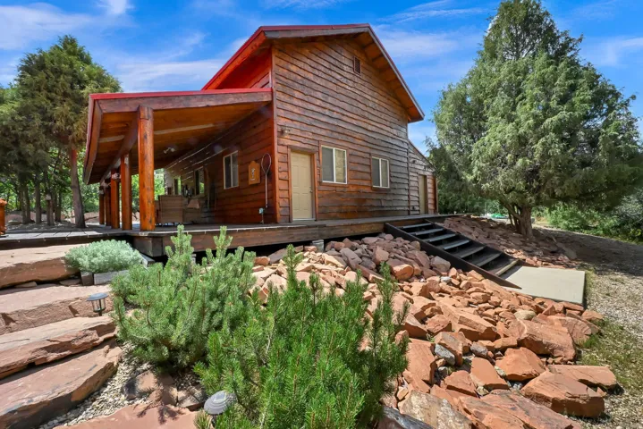 Wood-sided exterior featuring a red roof and an expansive covered porch supported by rustic log columns