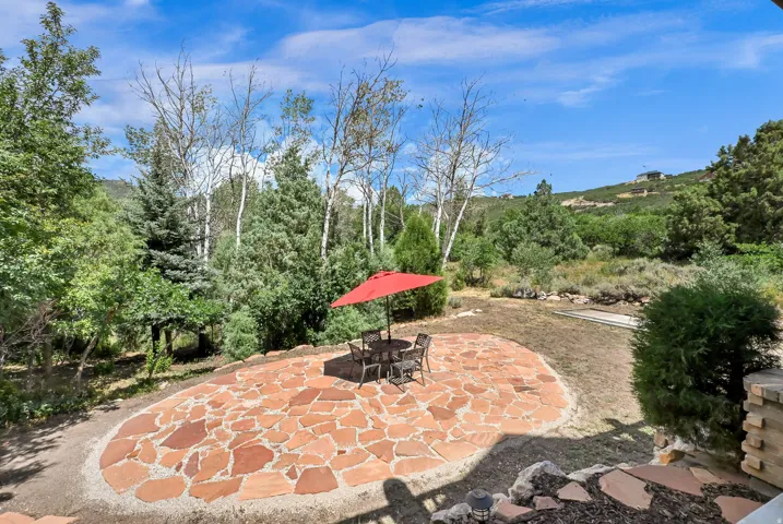 Expansive outdoor patio featuring irregular flagstone paving and natural landscaping