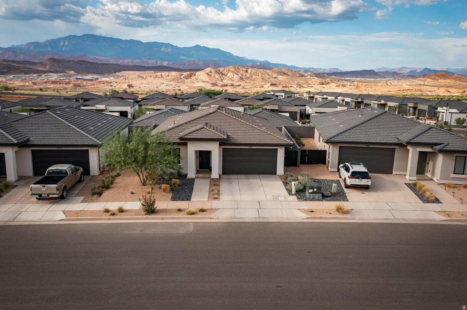 Contemporary desert-style residence featuring a prominent two-car garage, low-maintenance xeriscaping with decorative rock and native plantings, and a concrete driveway