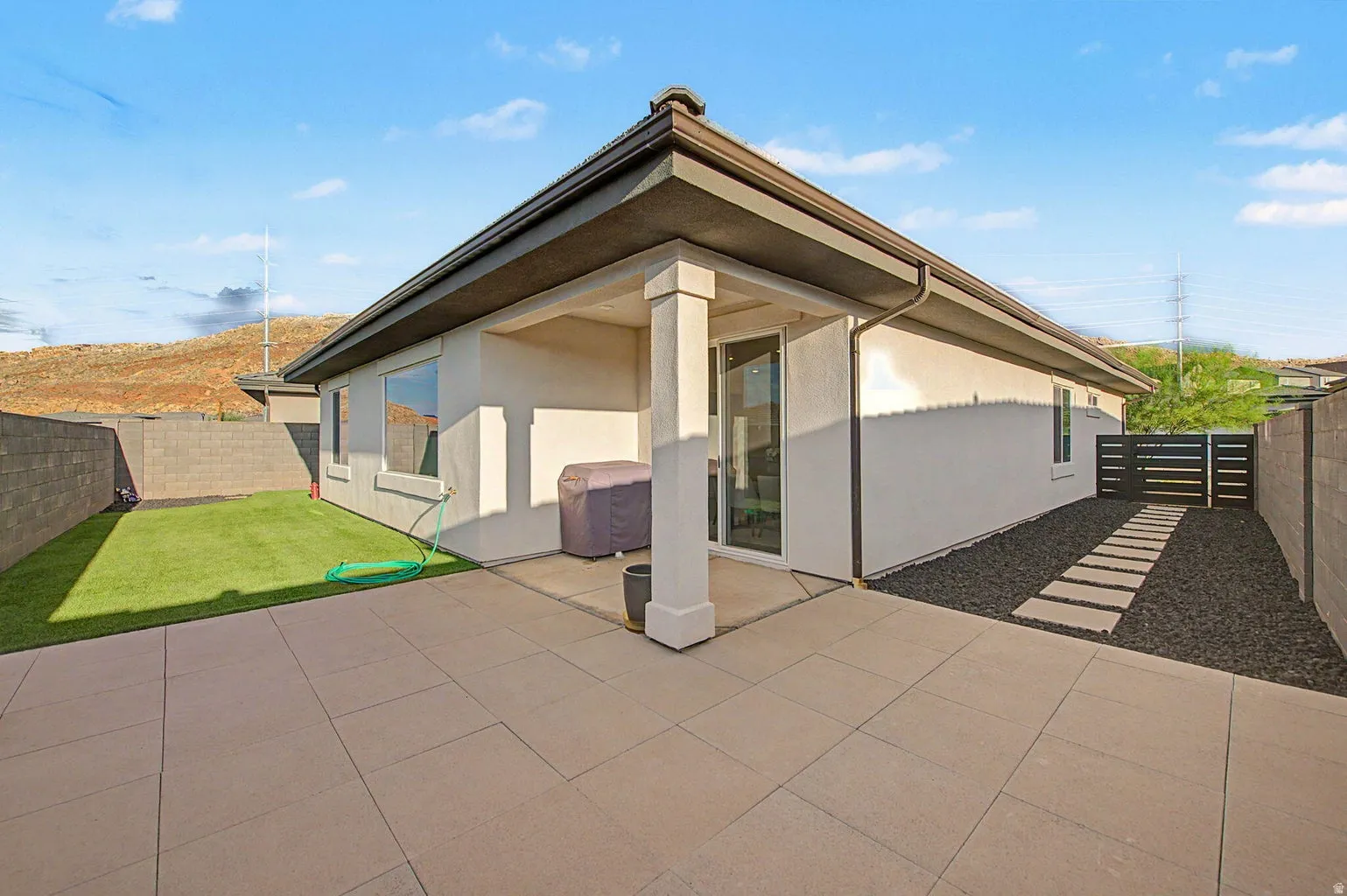 Spacious patio area with large format pavers, an artificial turf lawn, and a covered patio structure
