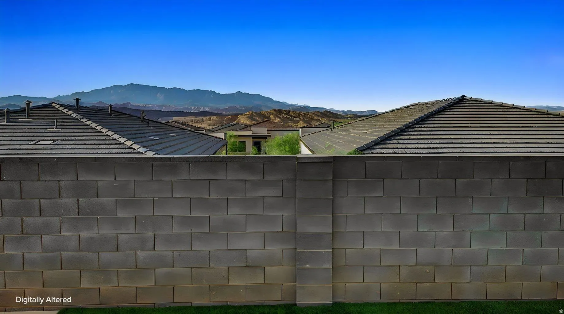 Block wall perimeter with distant mountain scenery under a clear sky