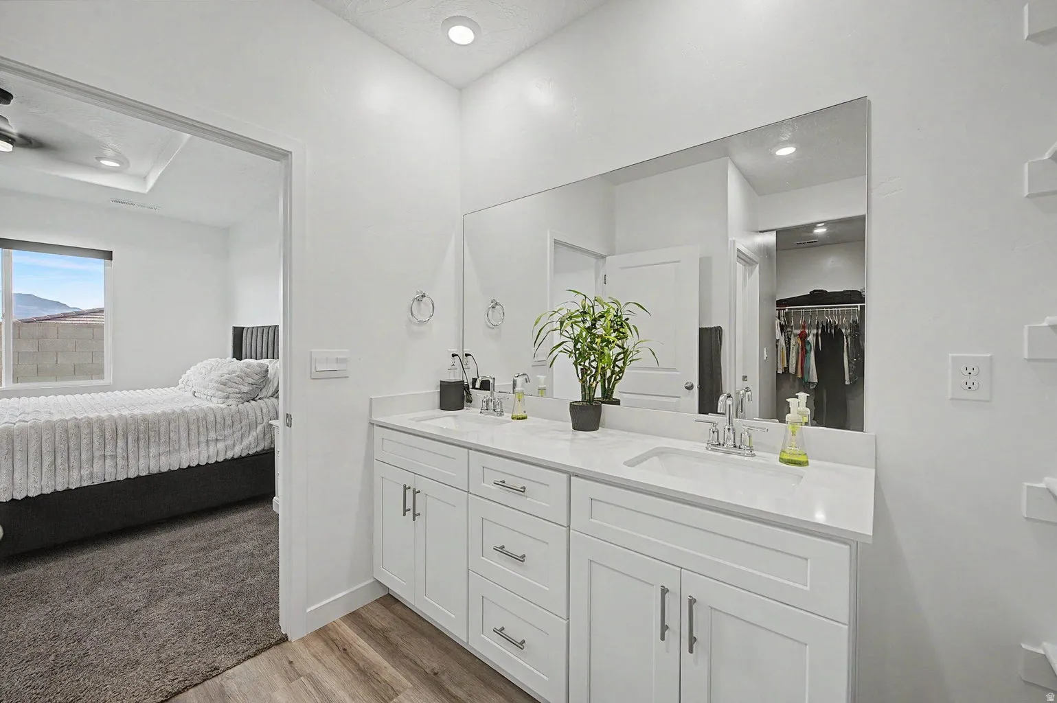 Double vanity with white cabinetry, integrated sinks, chrome fixtures, and a large wall-mounted mirror