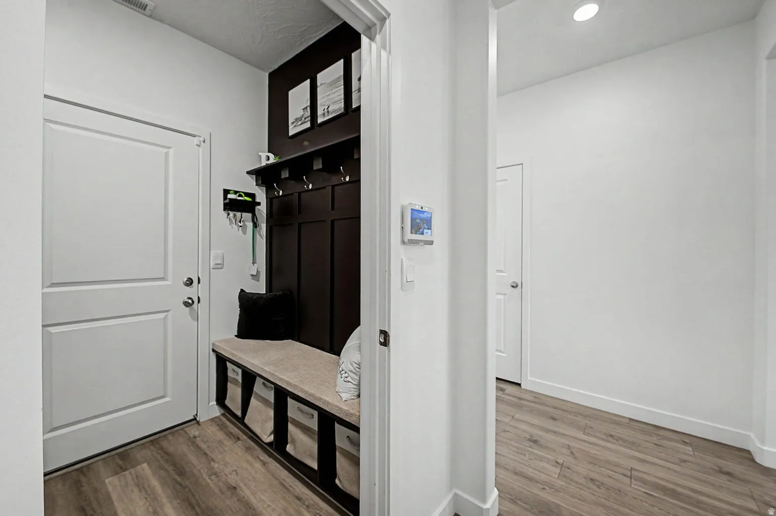 Entryway featuring wood-finish flooring, a built-in hall tree with hooks, and a bench with cubby storage
