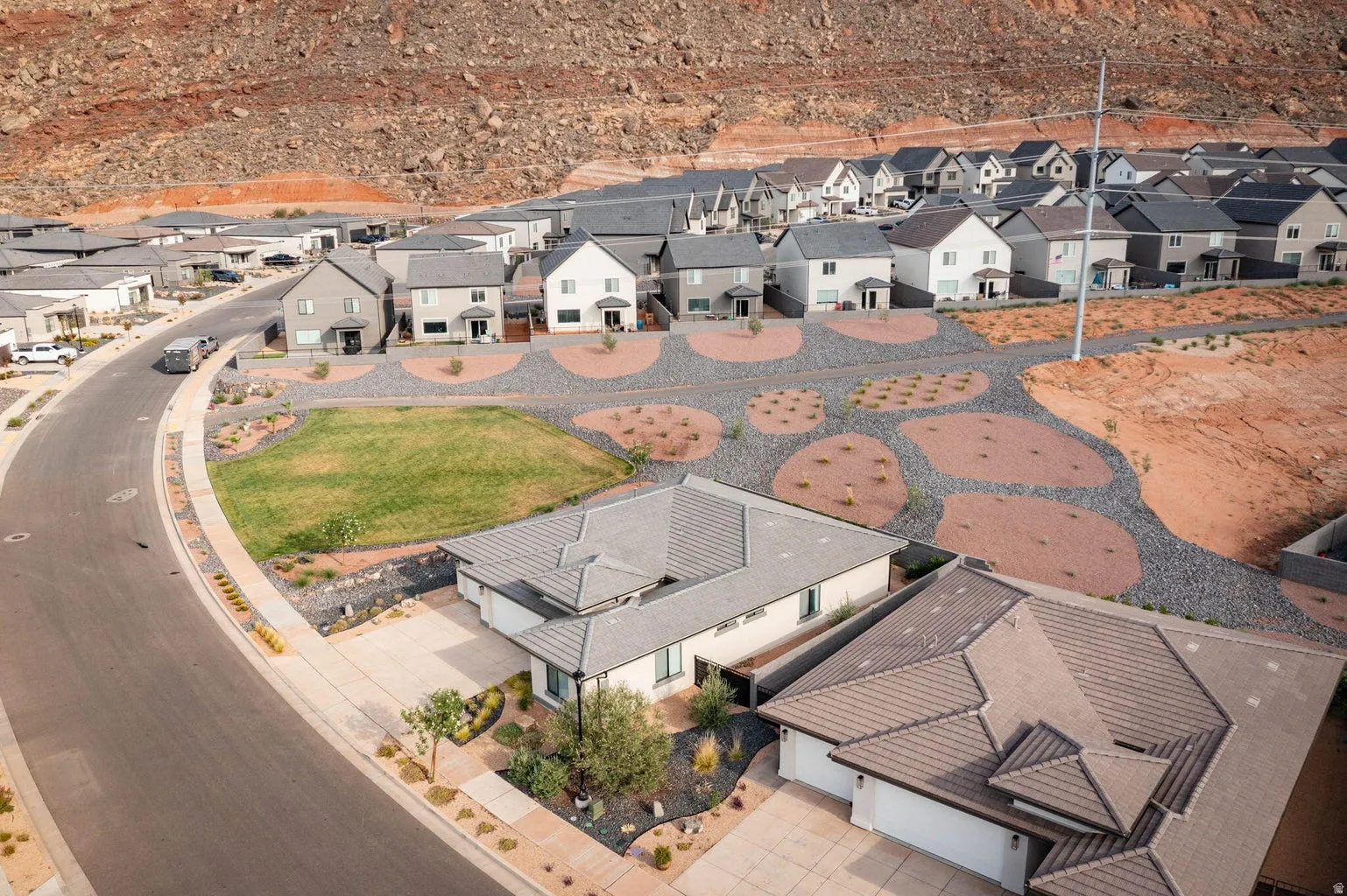 Modern residential development featuring a paved street, desert landscaping, and varied rooflines