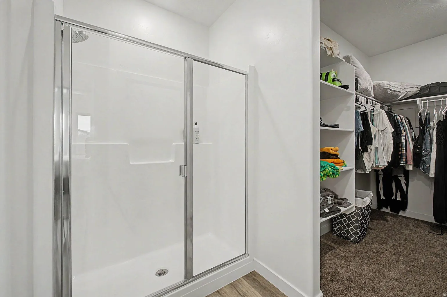 Walk-in shower with a glass enclosure and built-in shelving, complemented by wood-finish flooring