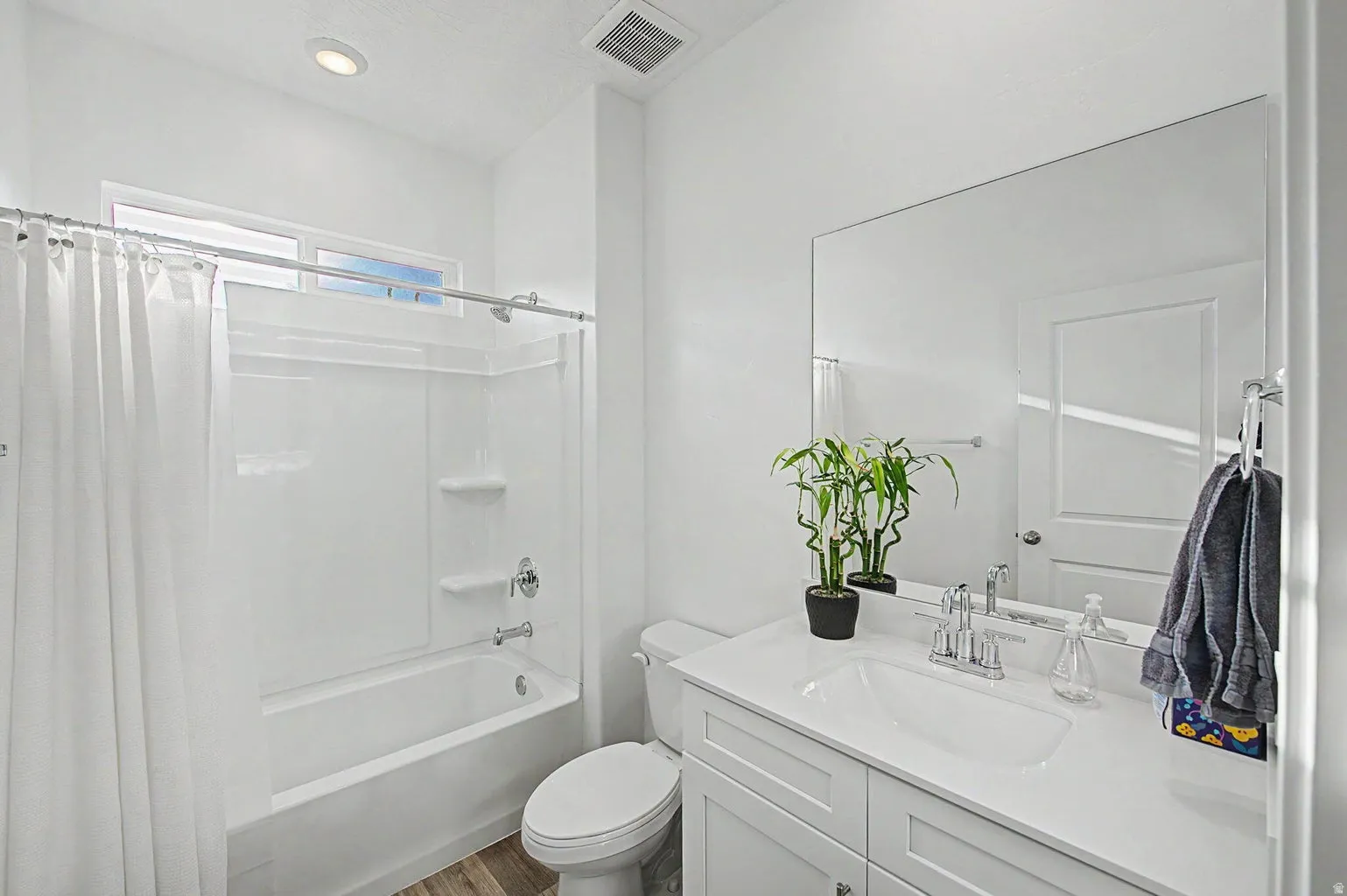 Bathroom featuring a full vanity with an integrated sink, polished chrome faucet, and a large wall-mounted mirror