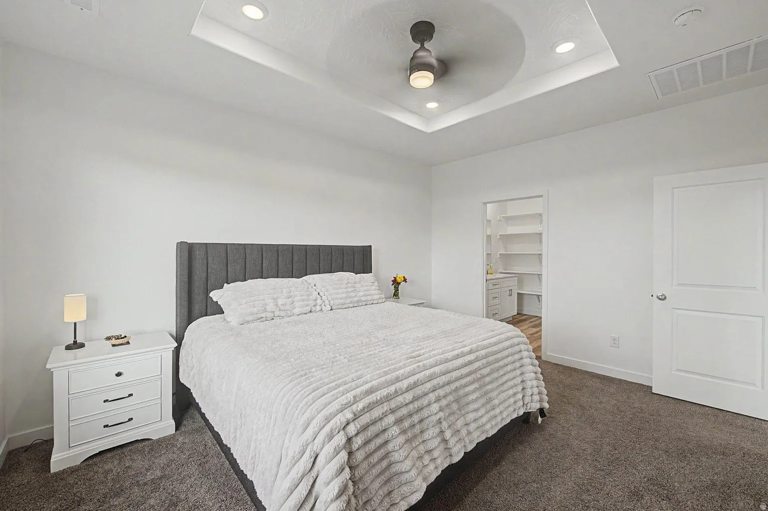 Bedroom featuring a tray ceiling with recessed lighting and a ceiling fan