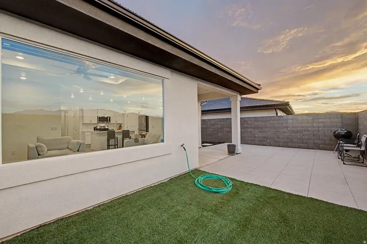 Expansive rear patio featuring concrete pavers, a privacy block wall, and synthetic turf