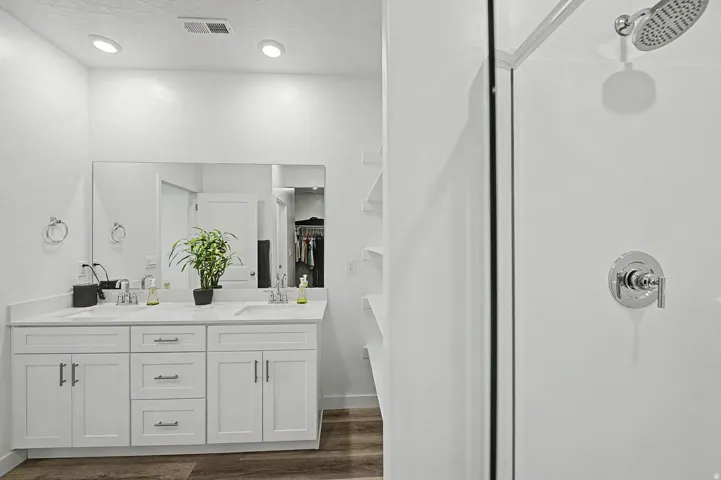 Bathroom featuring a dual-sink vanity with white cabinetry and a light-toned countertop