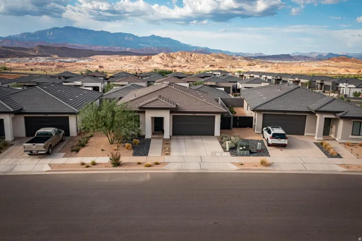 Contemporary desert-style residence featuring a prominent two-car garage, low-maintenance xeriscaping with decorative rock and native plantings, and a concrete driveway