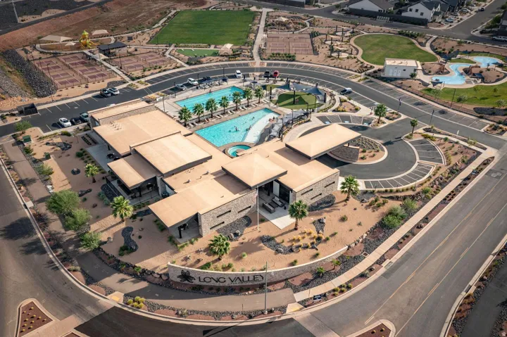 Community hub featuring a swimming pool, spa, tennis courts, and a central clubhouse with stone accents