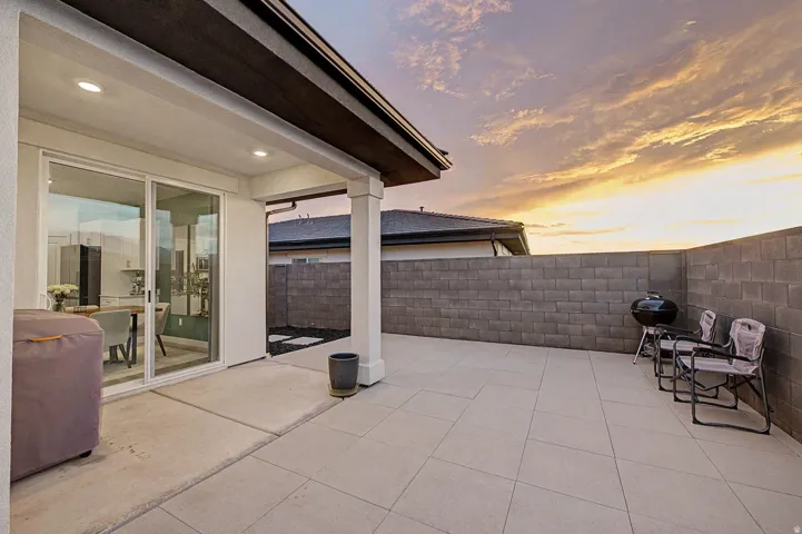 Spacious outdoor patio featuring large format tile flooring, a covered area with recessed lighting, and sliding glass doors