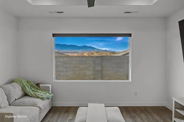 Interior space featuring a large picture window with mountain backdrop, wood-finish flooring, white baseboards, and a recessed ceiling panel
