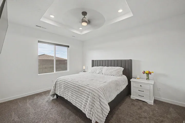 Spacious bedroom featuring a tray ceiling with recessed lighting and a ceiling fan