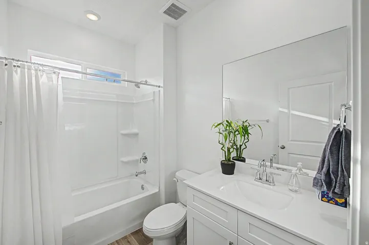 Bathroom featuring a full vanity with an integrated sink, polished chrome faucet, and a large wall-mounted mirror